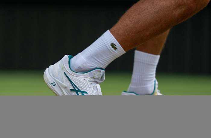 Novak Djokovic's white and green Lacoste tennis shoes.